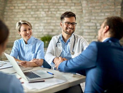 Happy doctor shaking hands with a businessman on a meeting in th